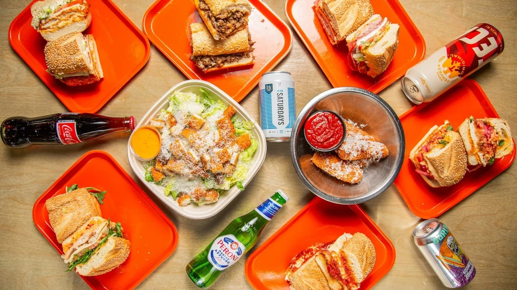 Overhead view of sandwiches, salad, fried food, and assorted beverages.