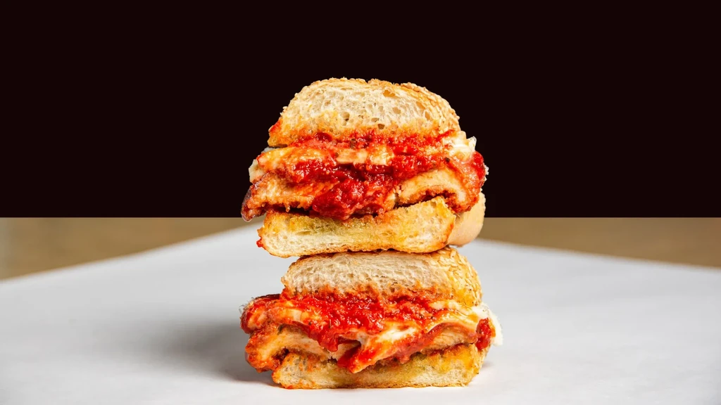 Stacked chicken parmesan sandwich halves with marinara and melted cheese.