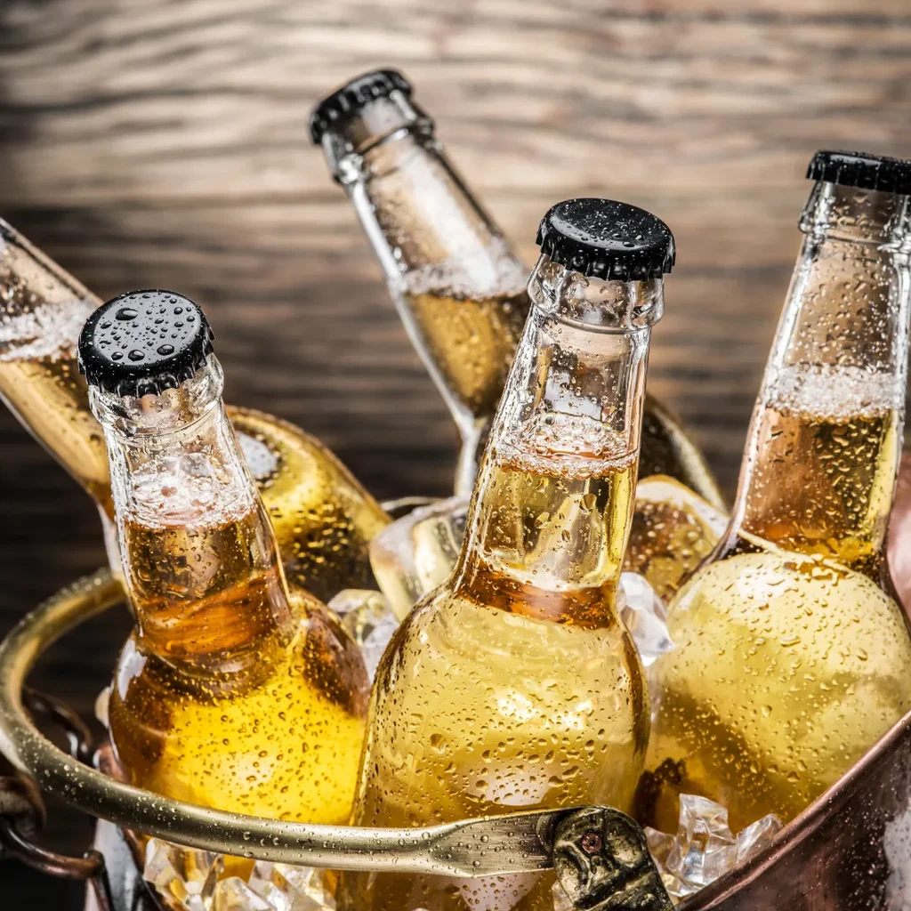 Condensation-covered golden beer bottles in a bronze ice bucket.