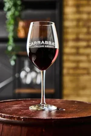 Close-up of red wine in Carrabba's glass on wooden barrel.