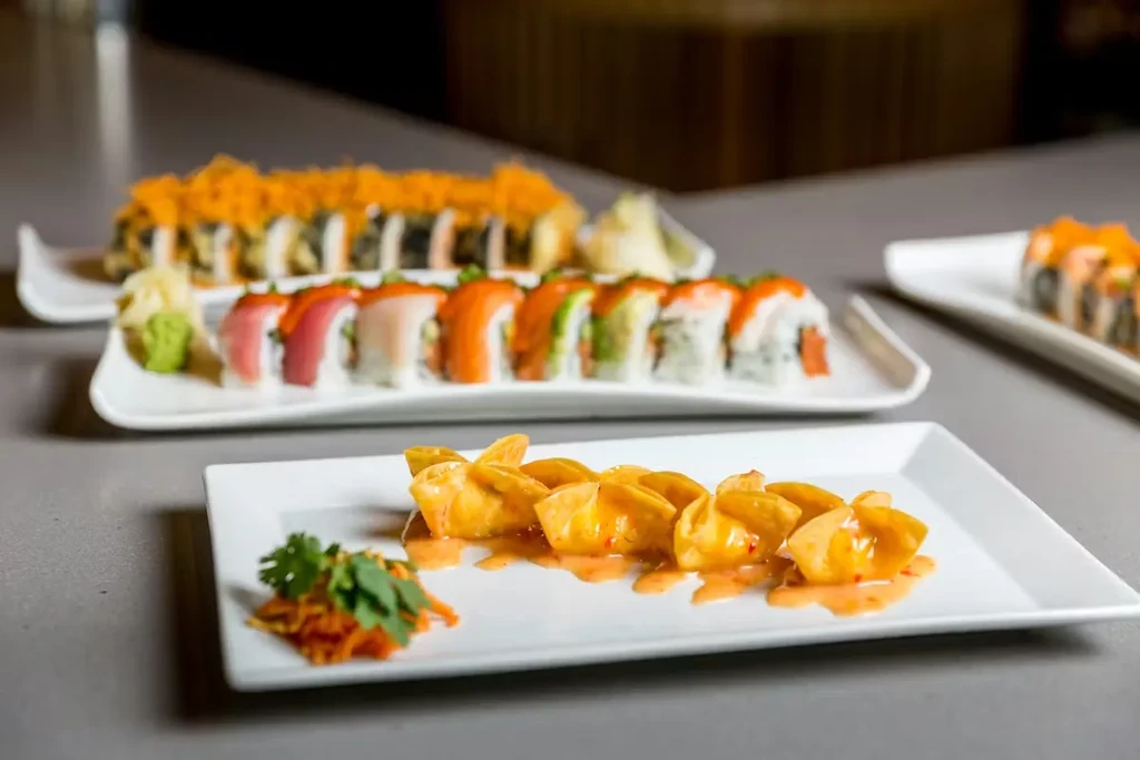 Assorted plates of Asian food: fried dumplings with sauce and sushi.