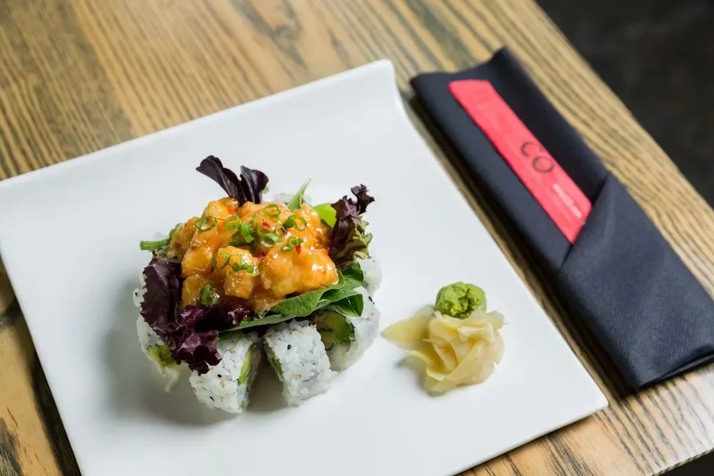 THOUGHT
The user wants alt-text for an image description.
The alt-text needs to be:
- Short (7-12 words)
- Factual
- No marketing language
- Concise and descriptive

Let's break down the key elements from the description:
1.  **Main subject:** Sushi roll
2
