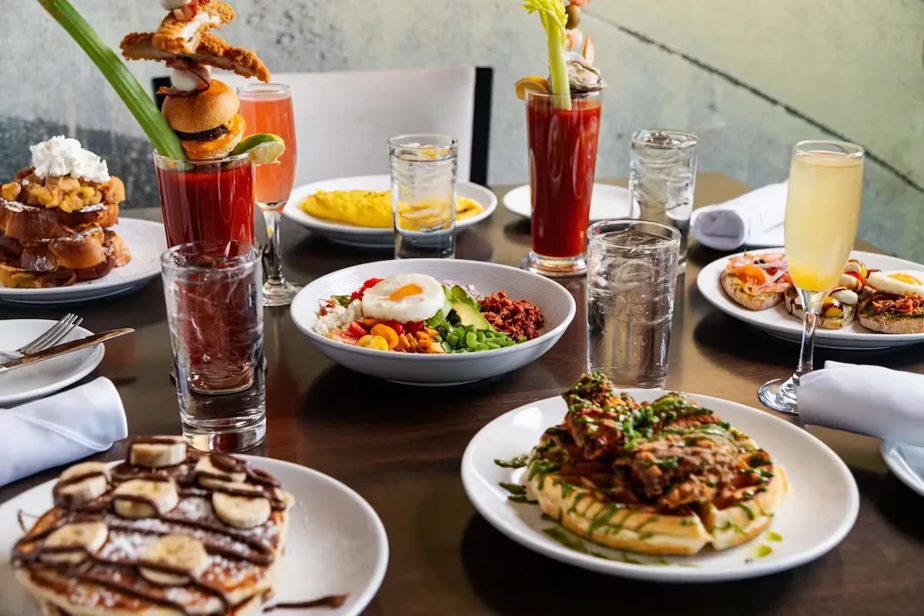 A table laden with various breakfast and brunch dishes and drinks.