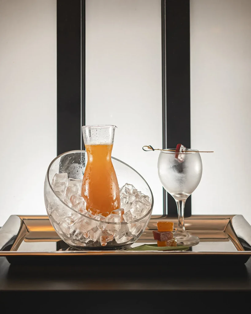 Orange juice in ice, a drink, and candies on a tray.