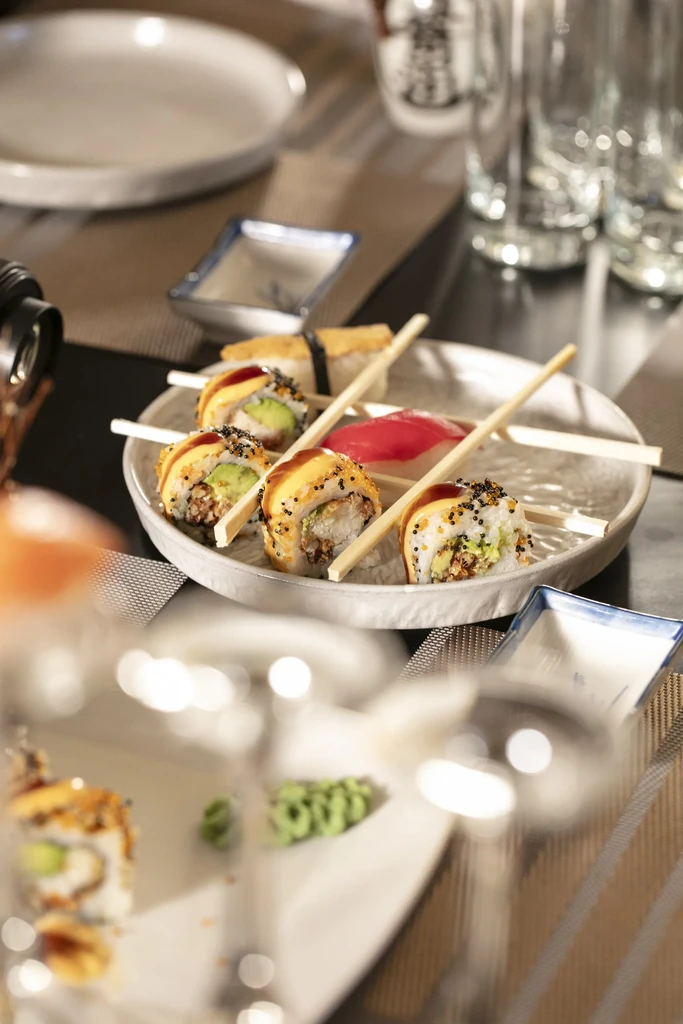 A plate of sushi rolls with chopsticks at a restaurant.