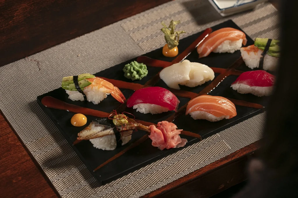 A black tray with assorted nigiri sushi, wasabi, and ginger.