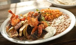Grilled shrimp and chicken fajitas with rice, beans, and sour cream.