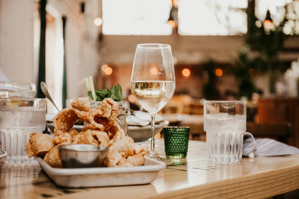 Crispy fried snacks, white wine, and cold water on a restaurant table.