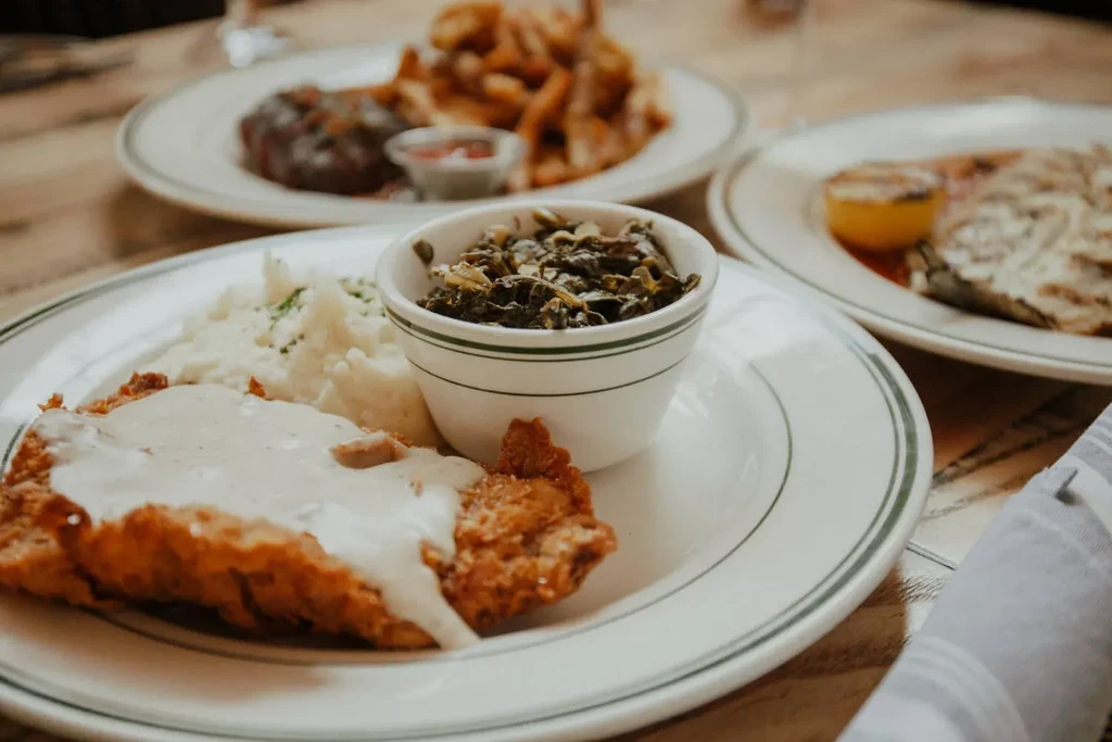 Close-up of a breaded cutlet, gravy, mashed potatoes, and collard greens.