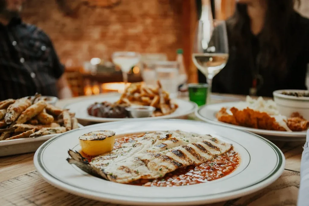 Grilled fish, steak, fries, and drinks on a restaurant table.