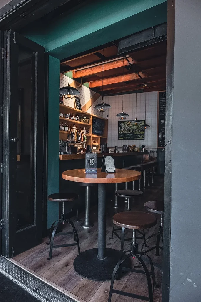 Upscale industrial bar interior with high-top table and exposed beams.