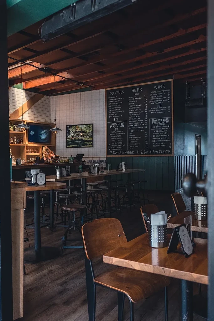 Cozy, dimly lit restaurant and bar with seating and a chalkboard menu.