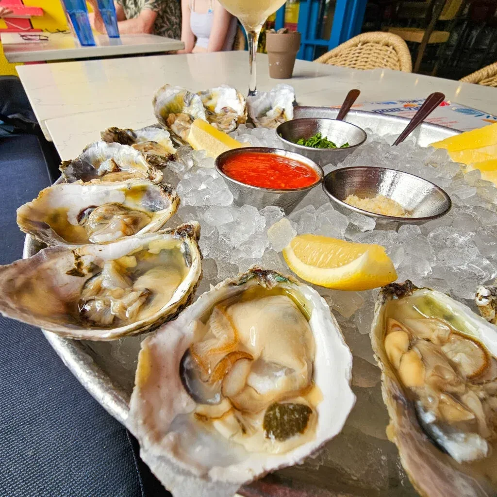 Fresh shucked oysters on ice with lemon and three dipping sauces.