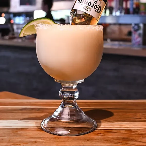 Margarita in a goblet with salted rim, lime, and inverted mini Corona.