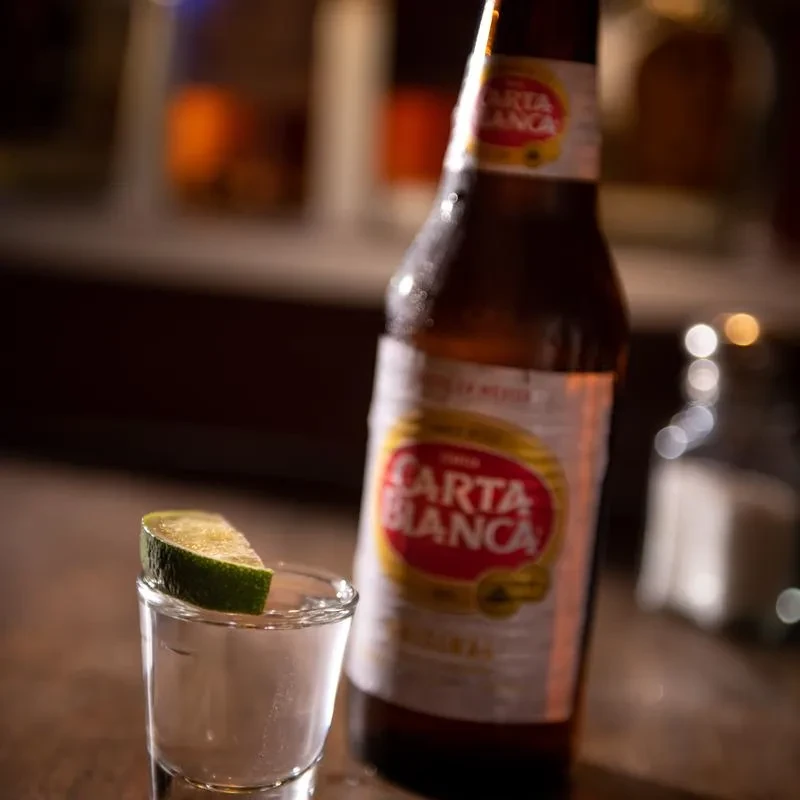 Cold Carta Blanca beer bottle and a shot glass with lime.