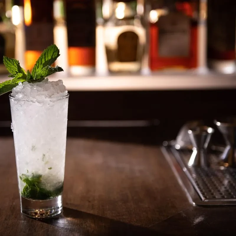 Mojito cocktail with mint and crushed ice on a dark bar.