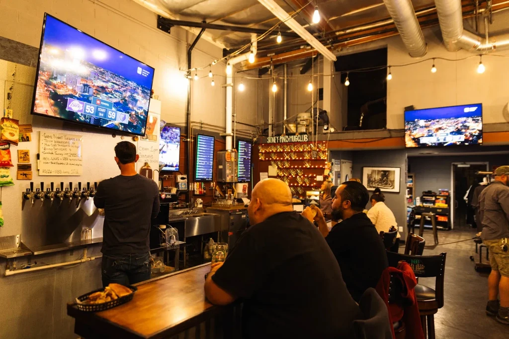 Lively industrial-chic bar with beer taps, patrons, and sports scores.