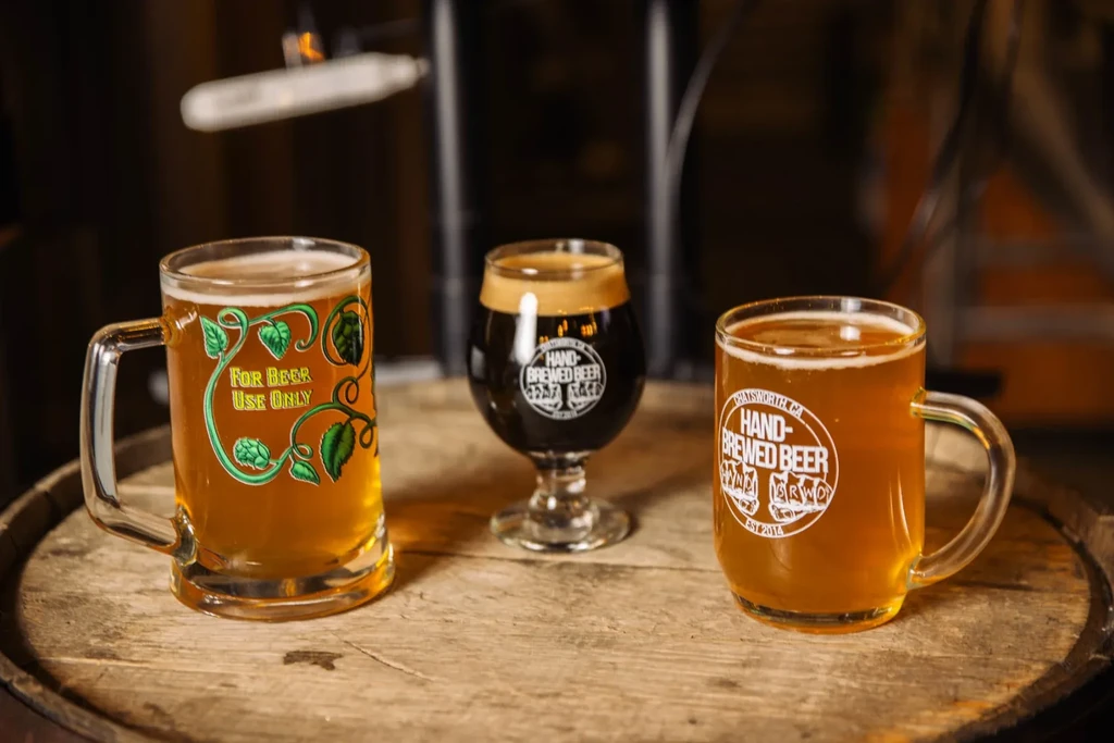 Three distinct beers on a rustic wooden surface in a brewery.