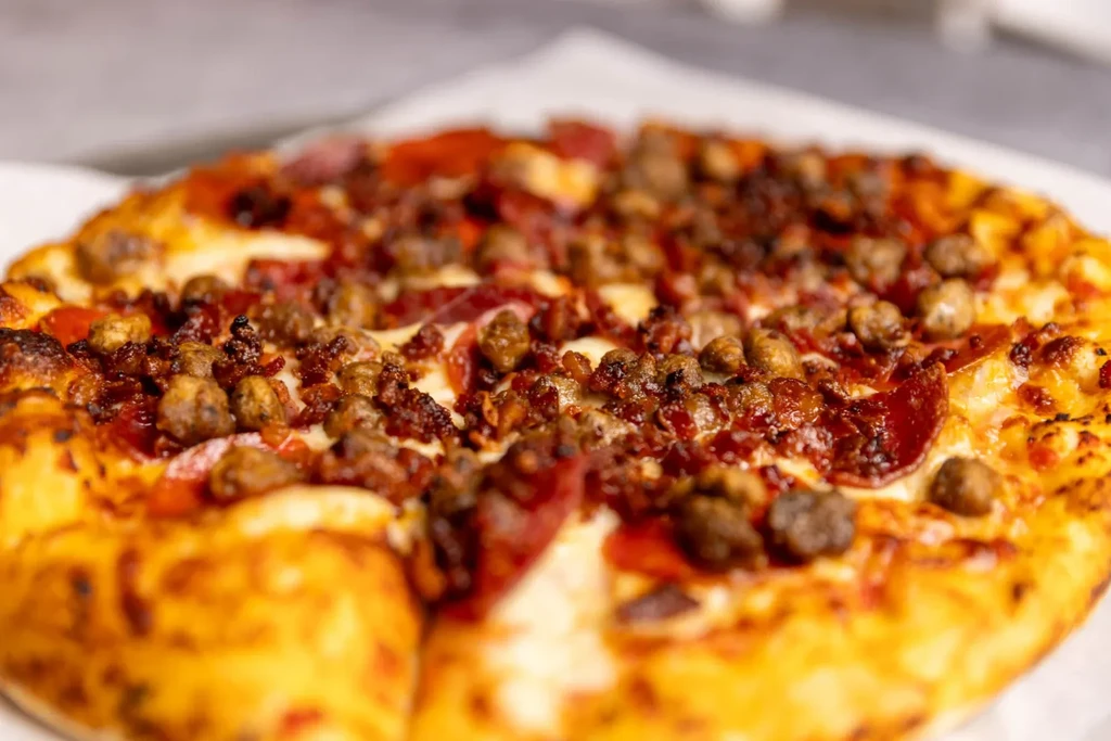 Whole meat pizza with pepperoni, sausage, melted cheese, and crispy crust.