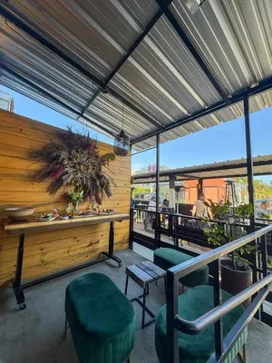 Restaurant patio with floral wall, appetizers, velvet stools, and blue sky.