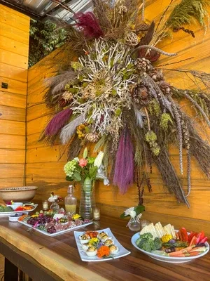 Rustic buffet table with cold cuts, deviled eggs, vegetables, and flowers.