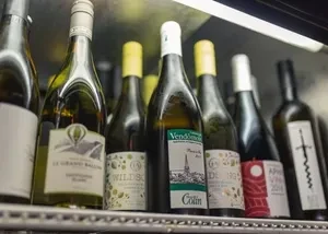 Close-up of neatly arranged white wine bottles on a metallic shelf.