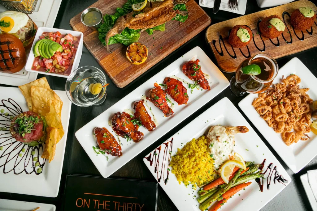 Flat lay of diverse restaurant dishes, drinks, and menu text.