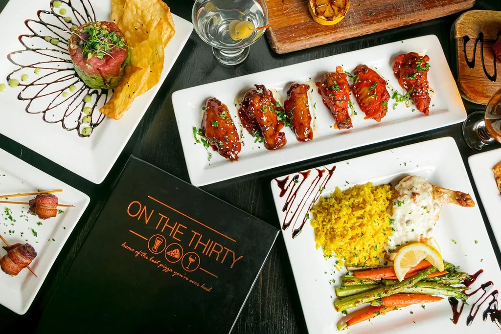 Flat lay of varied restaurant dishes, drinks, and a menu.