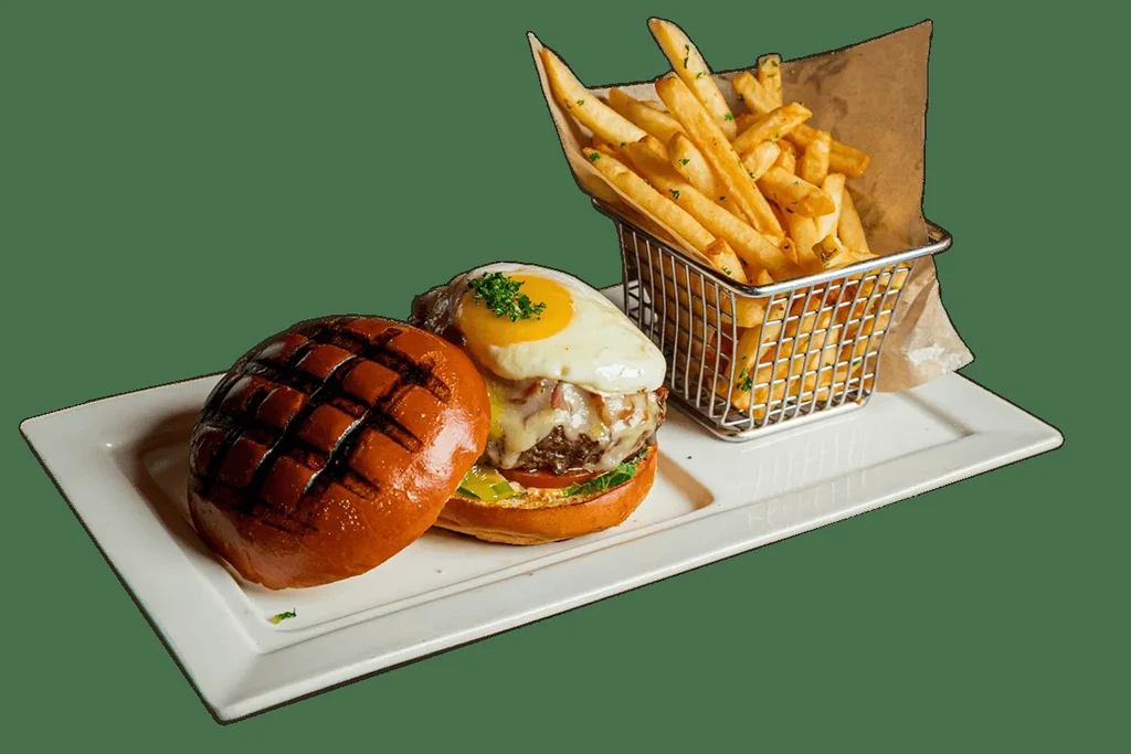 Gourmet burger with sunny-side-up egg and fries on a white platter.