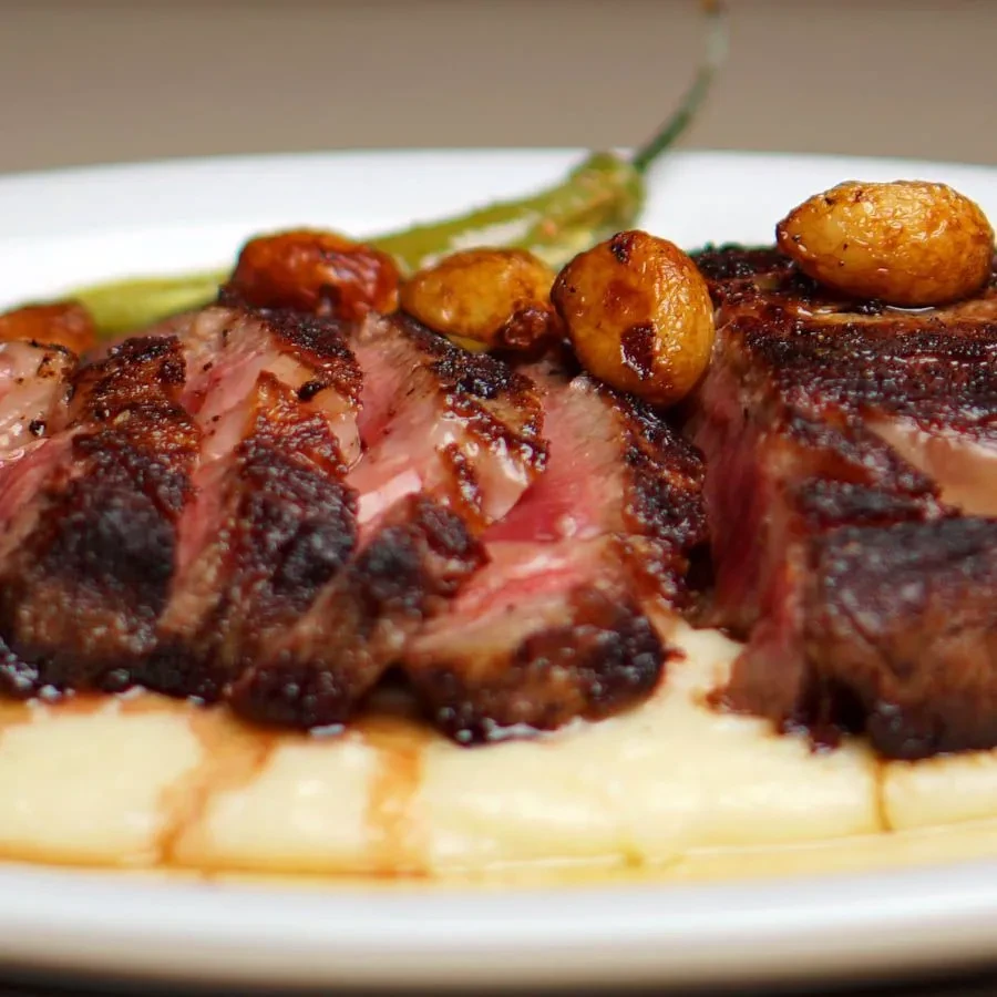Seared medium-rare steak on creamy puree with sauce and garlic.