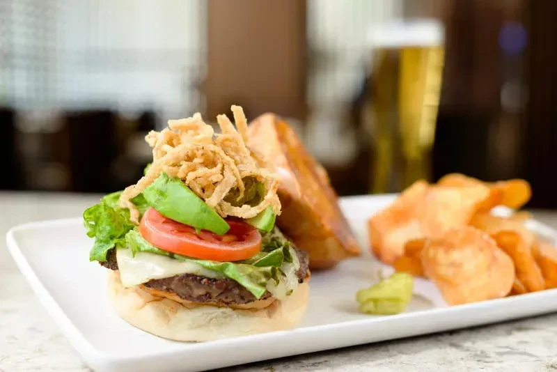Gourmet burger with avocado, onion strings, potato chips, and relish.