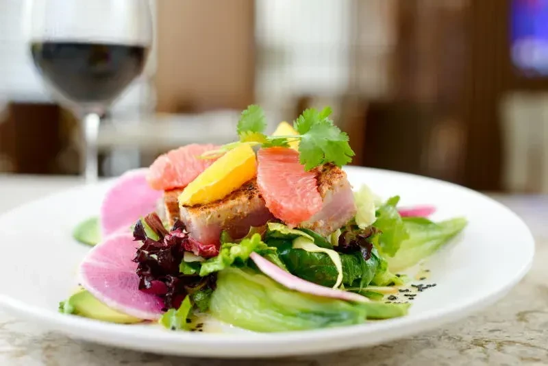 Plated seared tuna salad with grapefruit, avocado, greens, and radish.