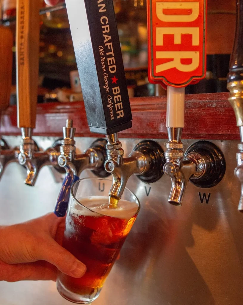 Hand holding glass as American Crafted Beer pours from a tap.