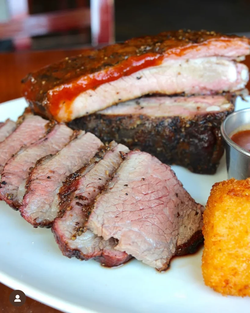 Close-up of saucy barbecued ribs and sliced smoked brisket on a plate.