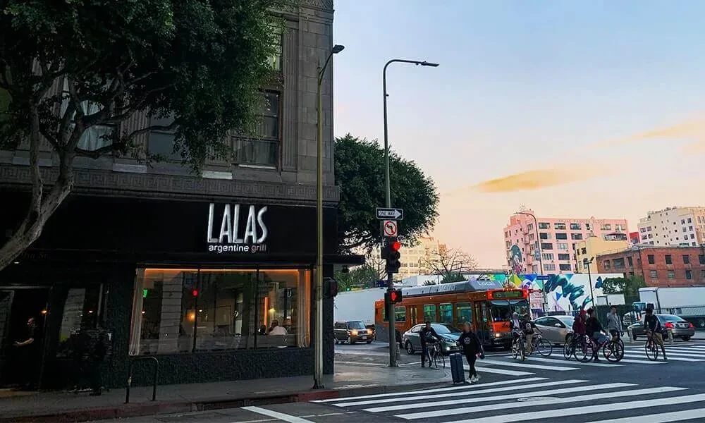 Lalas Argentine Grill exterior at dusk, with a busy city street.