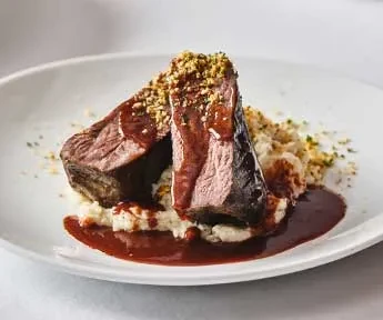 Plated braised meat, dark sauce, mashed potatoes, and crunchy topping.