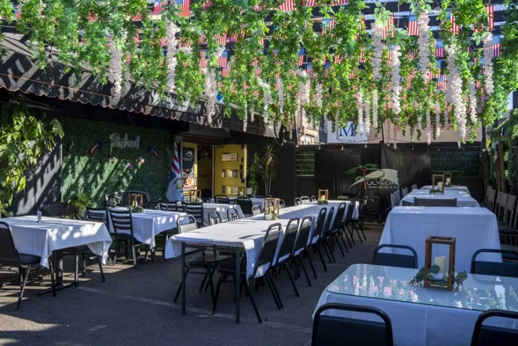 Elaborate outdoor dining canopy decorated with flags and white tables.