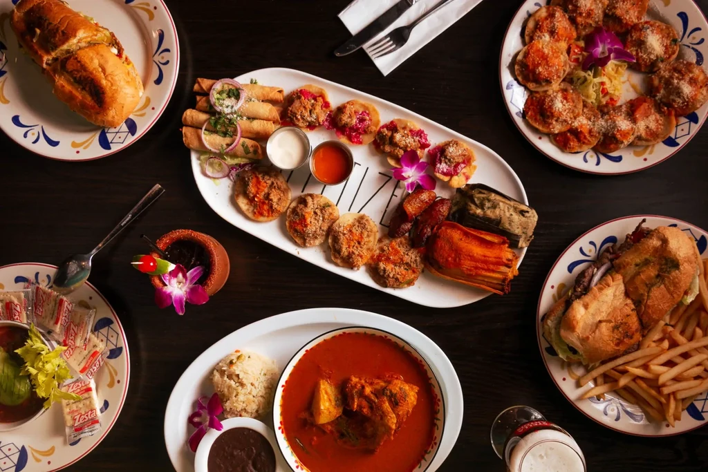 Overhead table shot with various Latin American dishes and drinks.