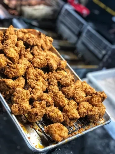 Crispy golden-brown fried chicken on a metal rack in a tray.