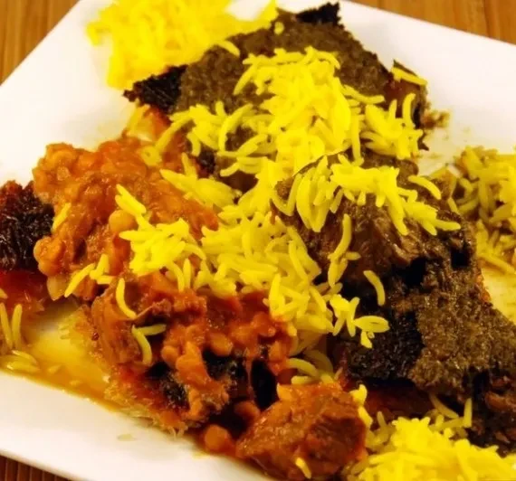 Top-down view of yellow rice, meat stew, and tahdig on a white plate.