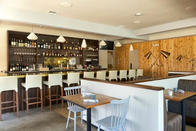 Modern empty restaurant interior with a well-stocked bar and diverse seating.
