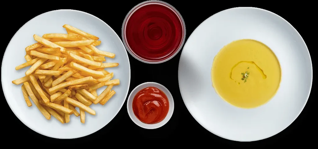 Top-down view of french fries, red drink, ketchup, and creamy soup.