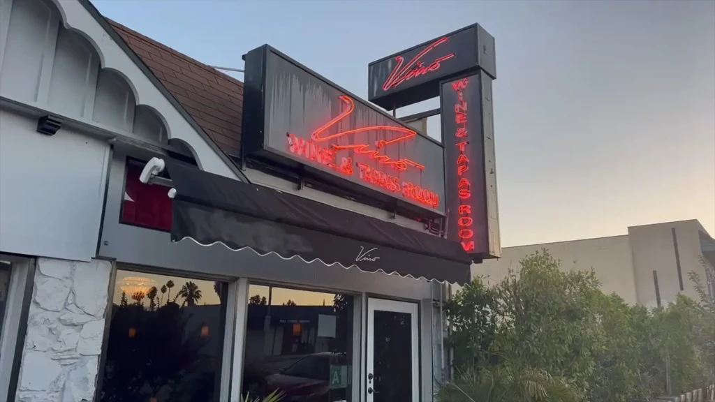 Vino Wine & Tapas Room exterior with glowing red neon signs at dusk.