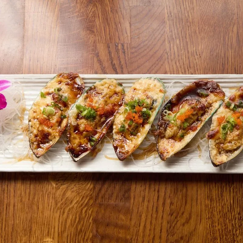 Six baked mussels in half-shells with gratin, roe, and green onions.