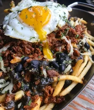 Loaded fries with meat, melted cheese, black beans, and fried egg.