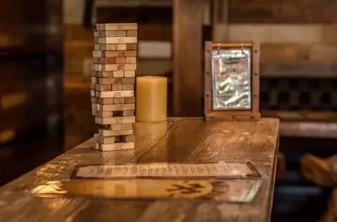 Wooden table with Jenga blocks, candle, and a menu.