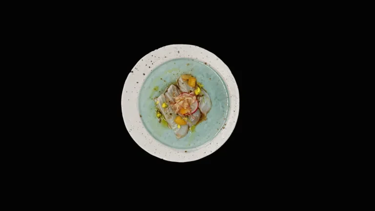 Sliced white fish, orange, radish, and shredded garnish on black.