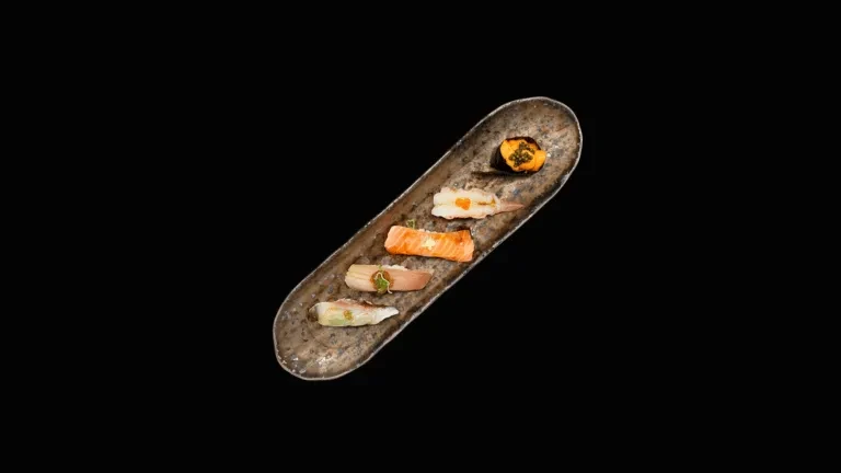Five distinct, colorful food pieces on a rustic plate, black background.