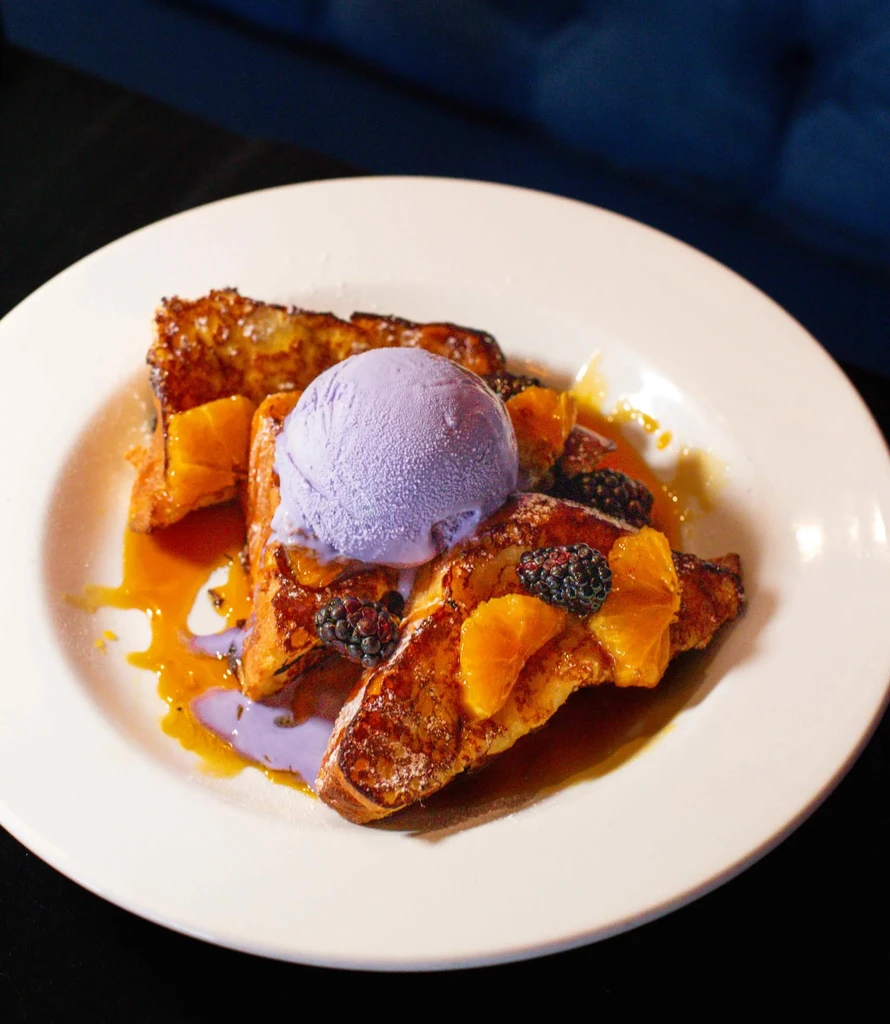 French toast topped with lavender ice cream, syrup, citrus, and blackberries.