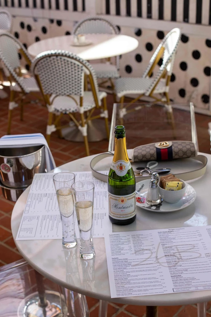 Marble table set with sparkling wine, two flutes, menus, and handbag.